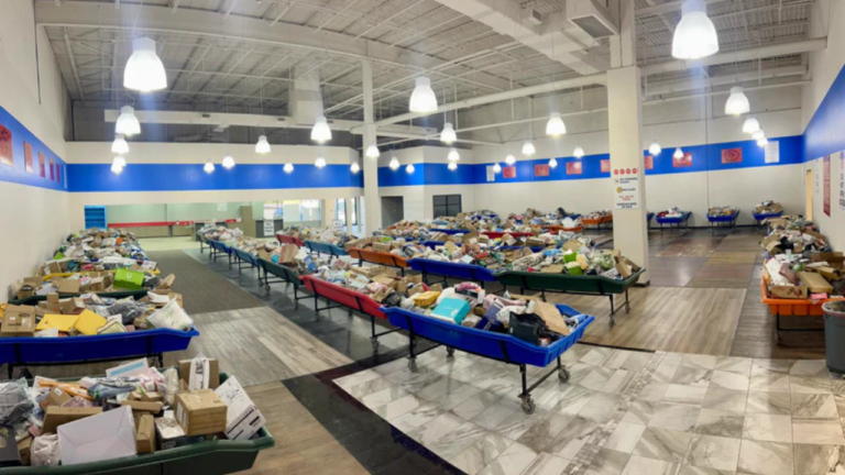 A spacious, brightly lit bin store with rows of colorful bins overflowing with assorted liquidation items, set on wheels and arranged neatly across a clean, open floor.